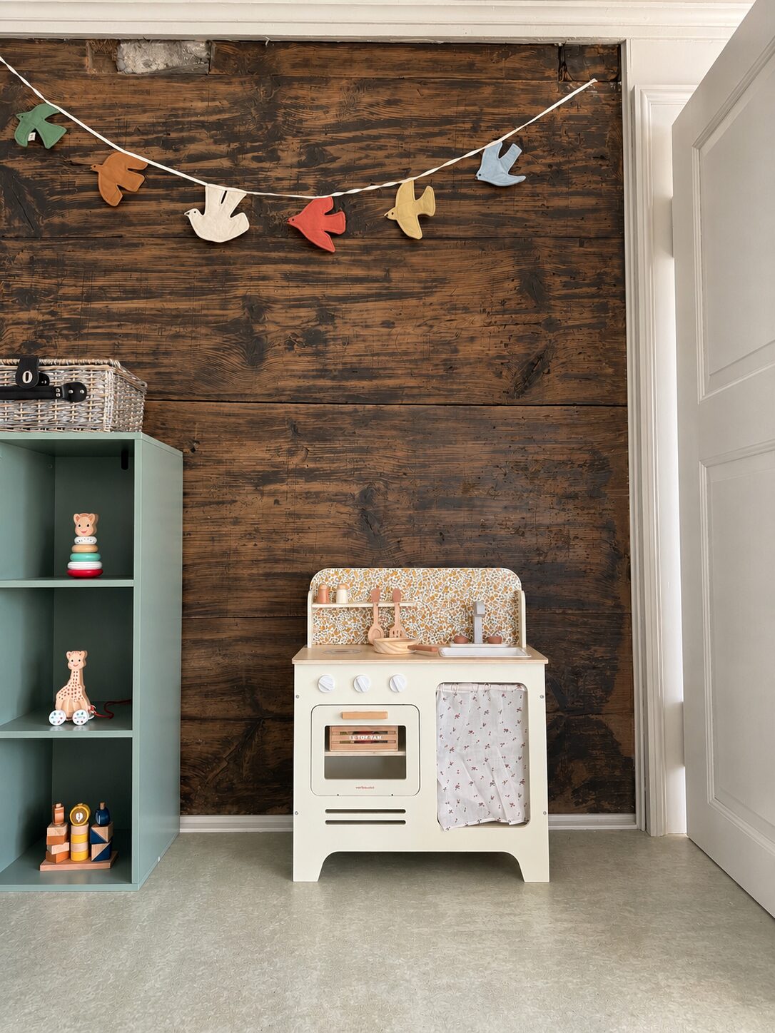 A wooden play kitchen and open shelves of natural materials in the group room